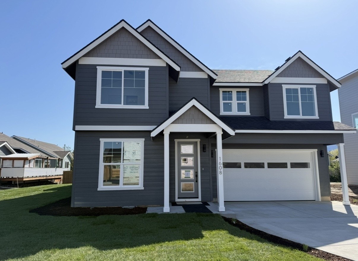 Completed new home exterior — lawn installed, driveway poured, garage door on, full curb appeal